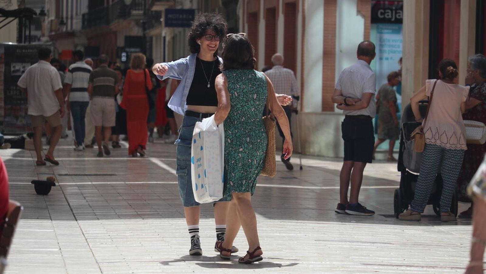 Dos onubenses se saludan con un abrazo al encontrarse en las calles de Huelva