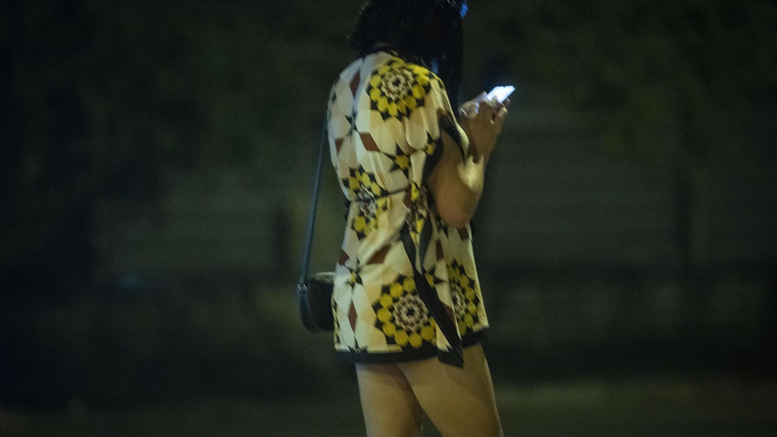 Una joven consulta su móvil mientras espera captar algún cliente.