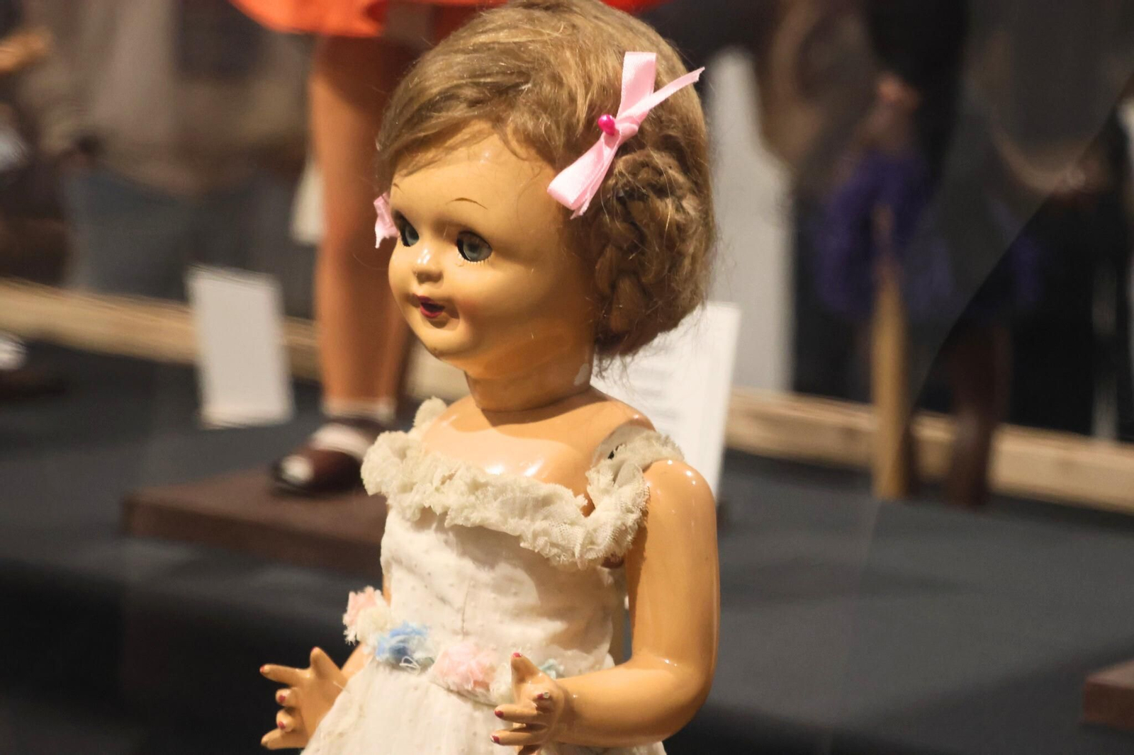 Primer plano de una muñeca clásica con lazo rosa, donde destacan los rasgos faciales y el peinado característicos de la producción artesanal de la época.