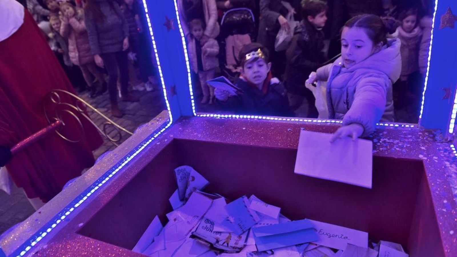 Niños depositan sus cartas en la carroza del emisario.