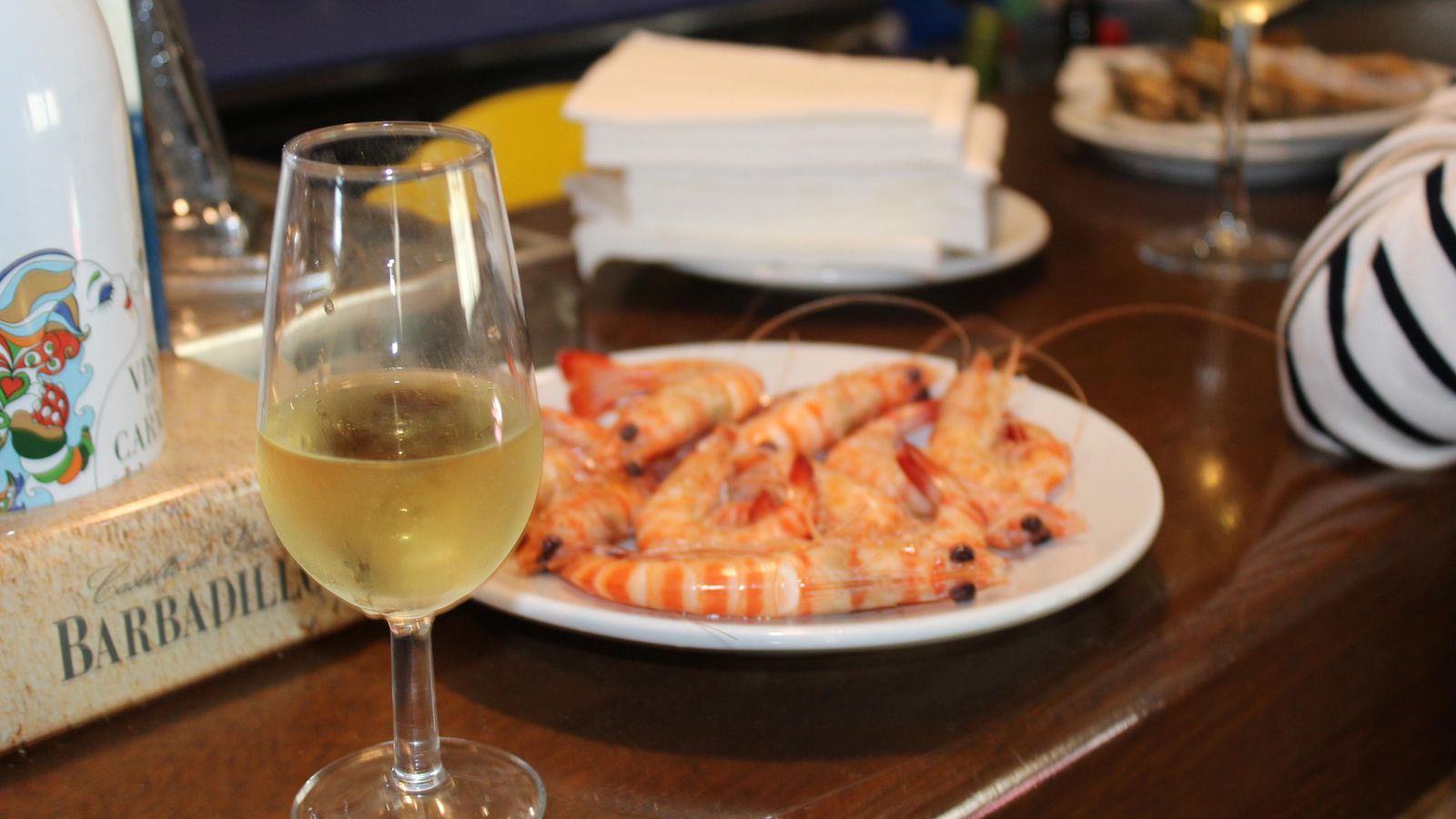 Copa de manzanilla a granel servida en catavino y langostinos de Sanlúcar en la barra de 'Joselito Huerta'.