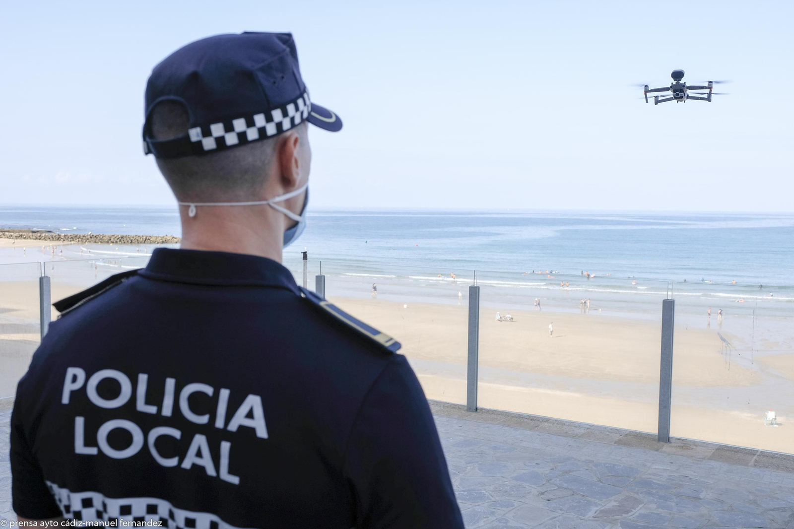 Un policía local vigila el vuelo de un dron en Santa María del Mar.