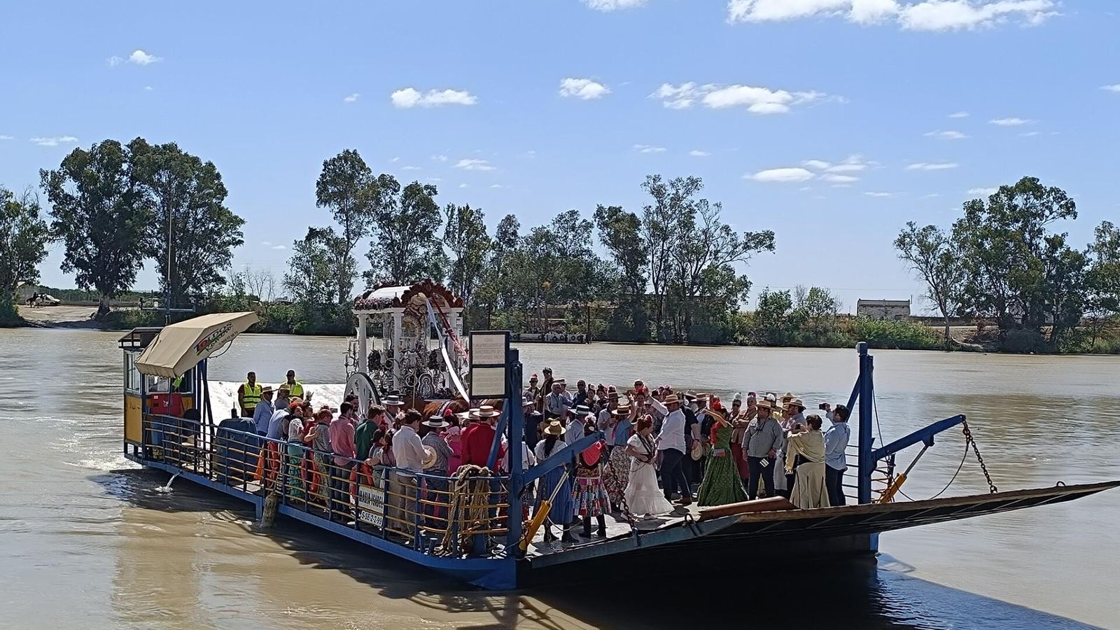 La carreta de Ronda cruza con su peregrinos el Guadalquivir en barcaza.