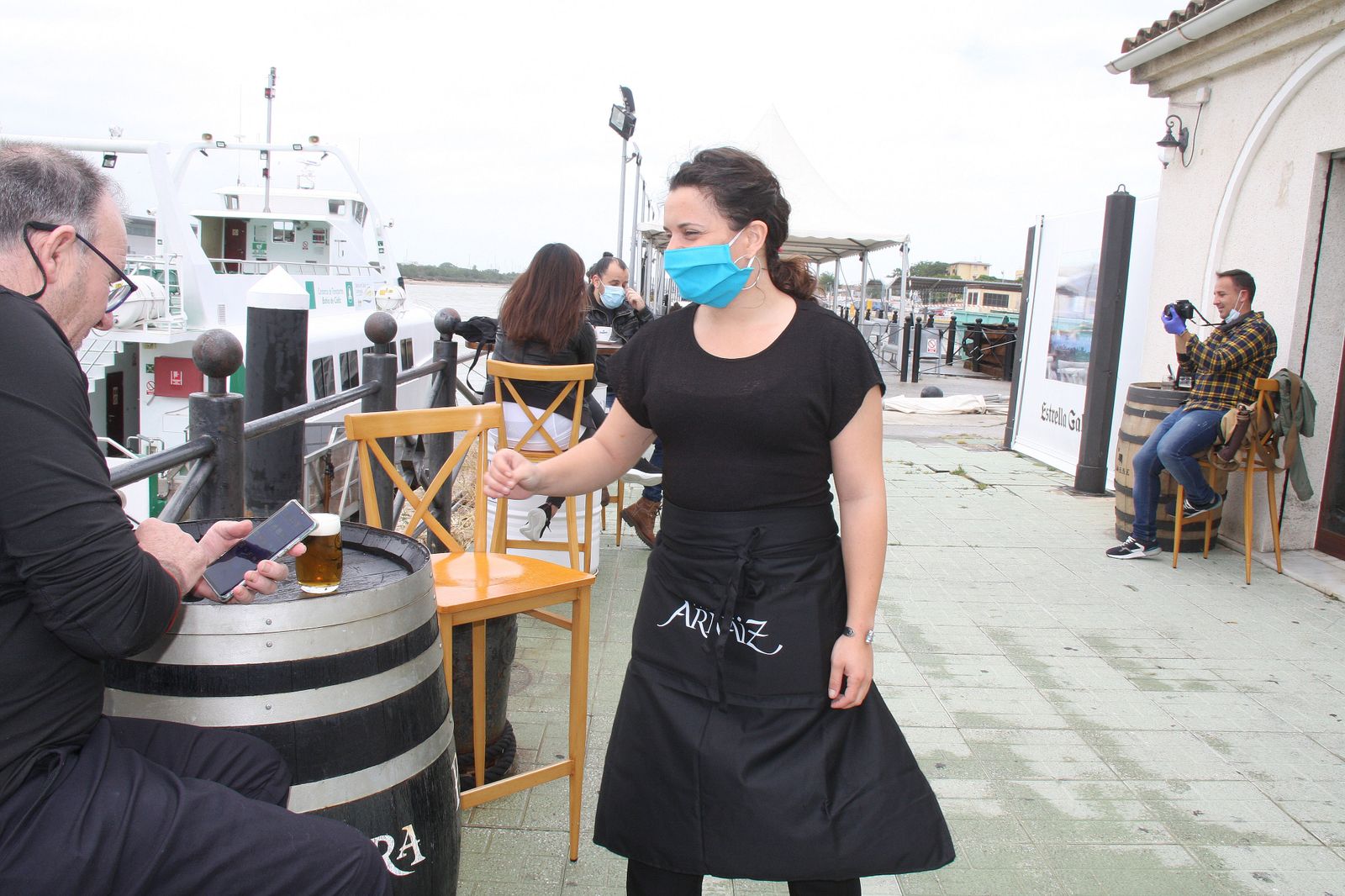 La dueña del establecimiento atiende a un cliente en la terraza del Bar La Jara.
