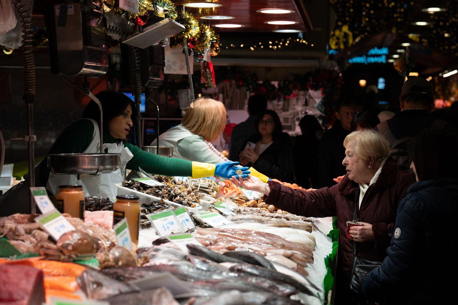 Una comerciante cobra a una señora en el mercado.