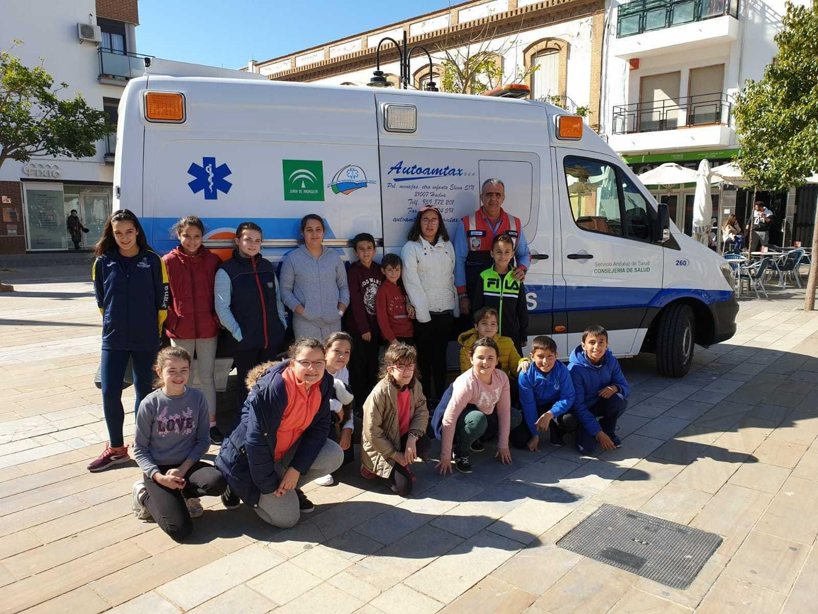 Alumnos del colegio San Juan Bautista en la plaza de España de San Juan del Puerto, con una ambulancia.