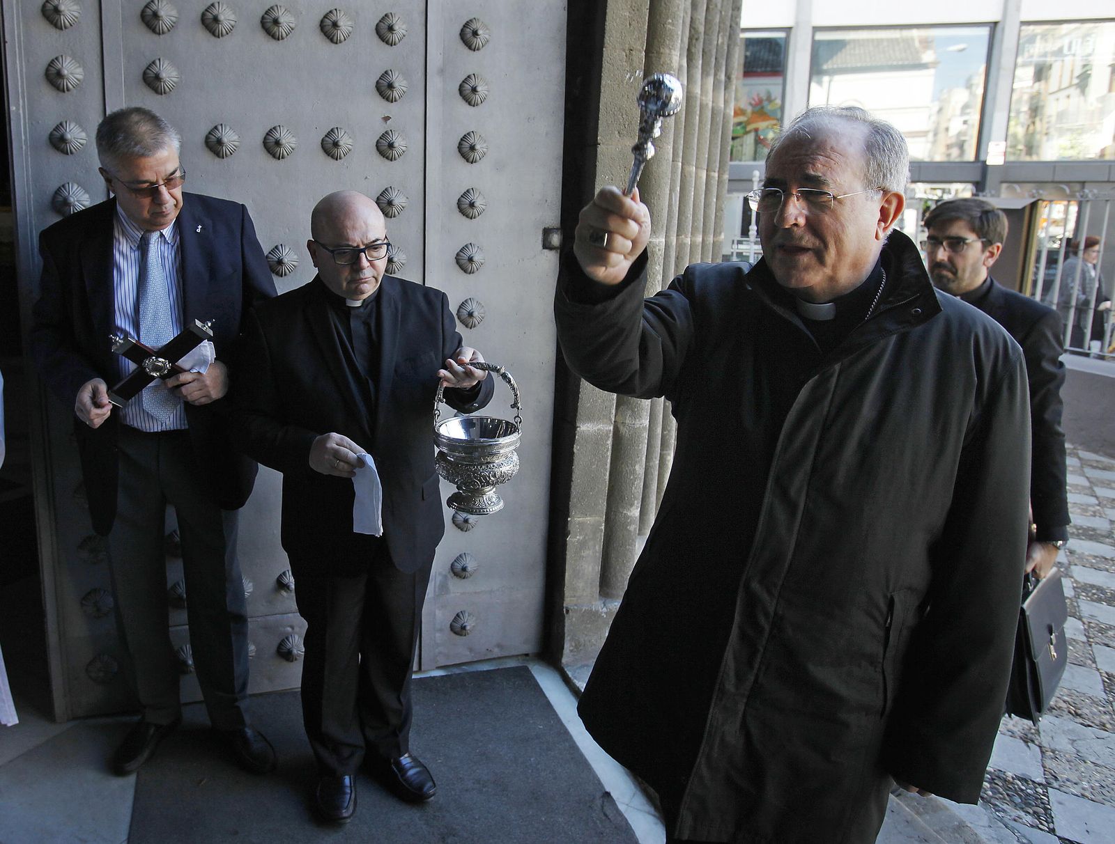El arzobispo de Sevilla entre en la iglesia de Ómnium Sanctórum, junto al párroco y el diácono.
