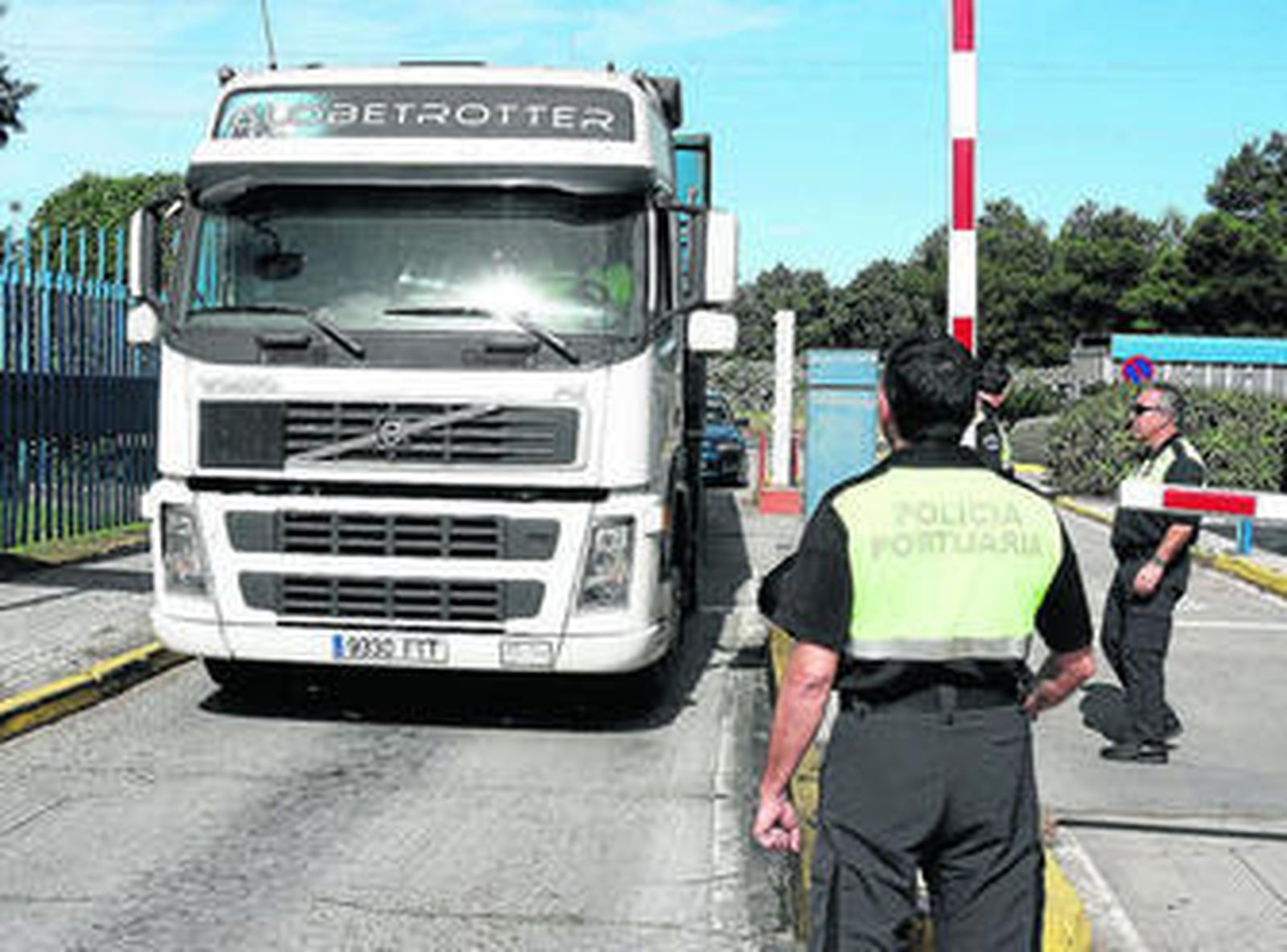 1. Policías portuarios controlan la entrada de camiones en el Puerto Oeste, la mañana del pasado jueves. El acceso de vehículos pesados a los muelles es continuo y el control está habilitado las 24 horas durante todos los días del año. 2. Un agente de este cuerpo recibe y transmite instrucciones por la emisora junto a su vehículo en uno de los muelles del Puerto de Sevilla. 3. Un policía portuario, dentro de su coche patrulla en las instalaciones portuarias, con una enorme grúa al fondo.