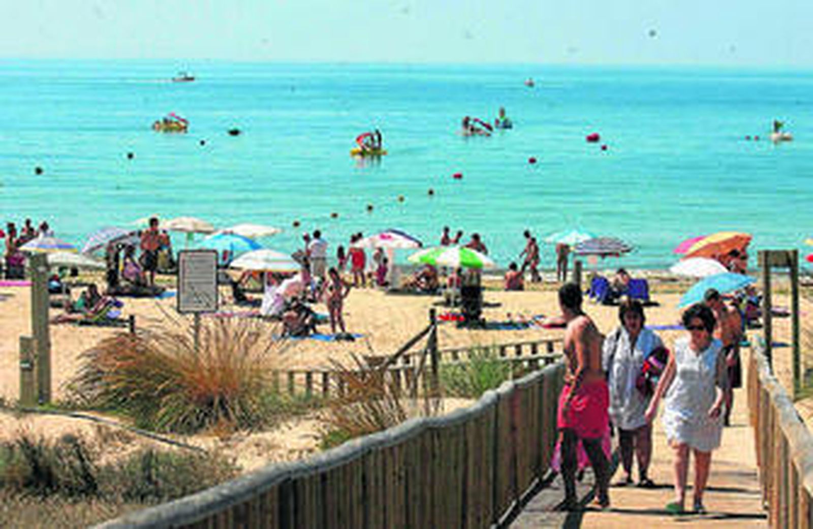 Bañistas suben una rampa de una playa en la provincia de Huelva.