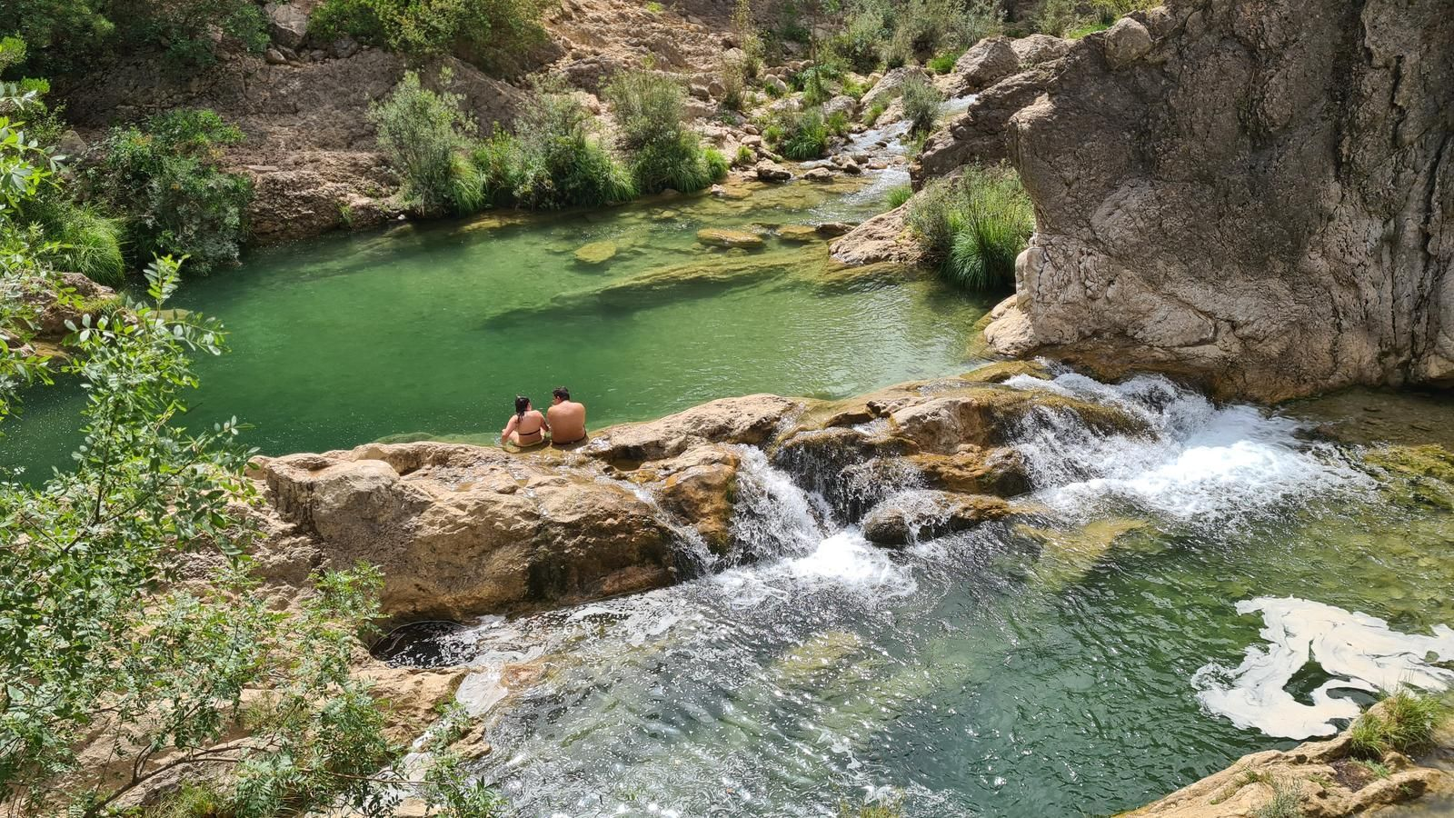 Senderistas disfrutando de las cristalinas pozas del Río Borosa en un caluroso día de verano.