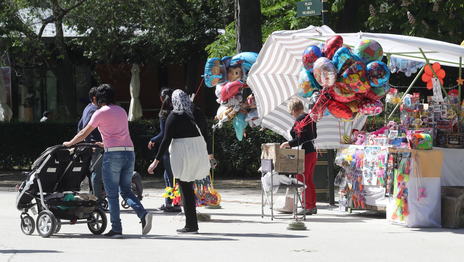 Una mujer pasea con el carrito  de sus hijos en el madrileño parque de El Retiro.