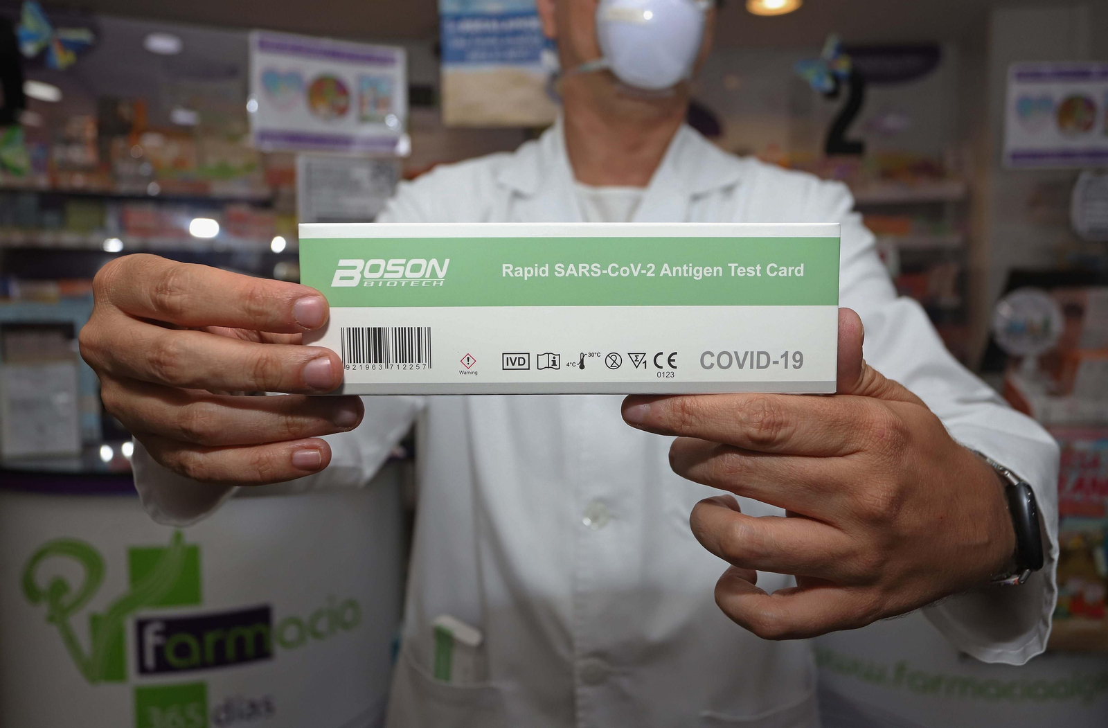 Un farmacéutico muestra una caja de test de detección del Covid.