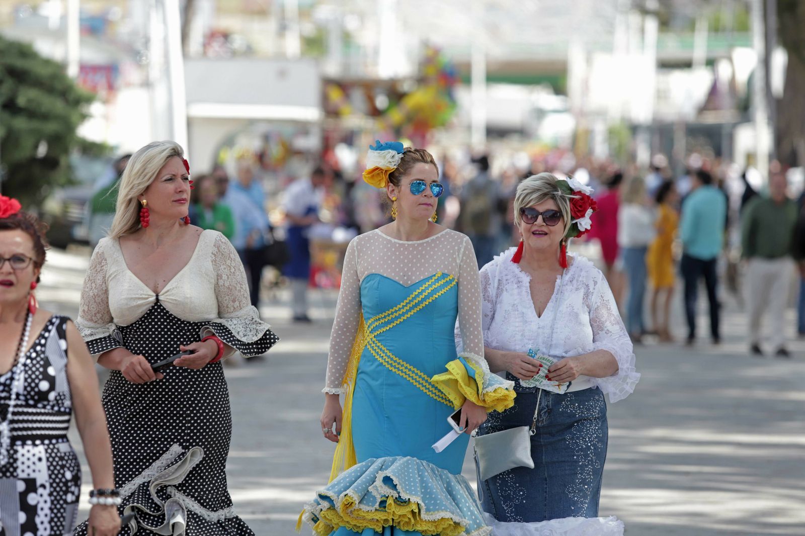 Tres mujeres vestidas de flamenca pasean por la Feria de Los Barrios en la pasada edición.