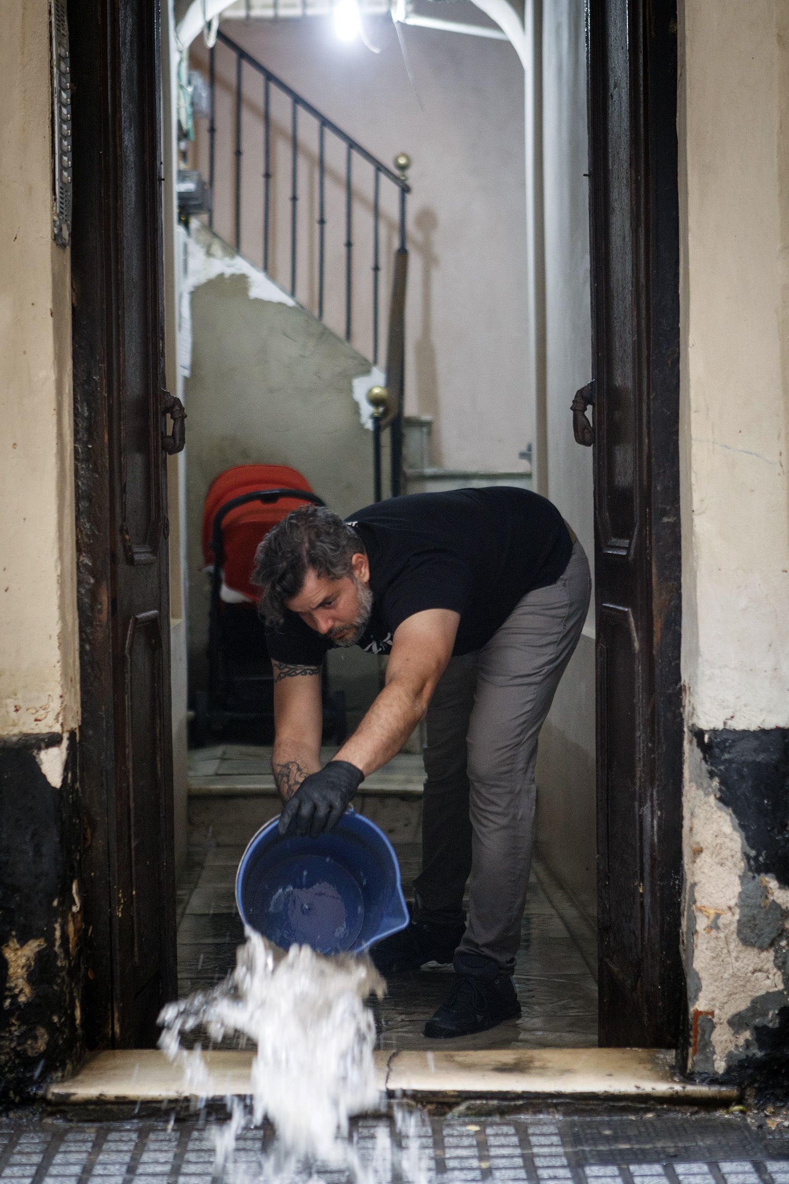 Un hombre saca agua de su casa a cubos.