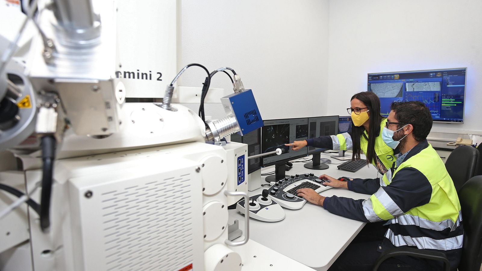 Dos técnicos  trabajan con un microscopio electrónico.