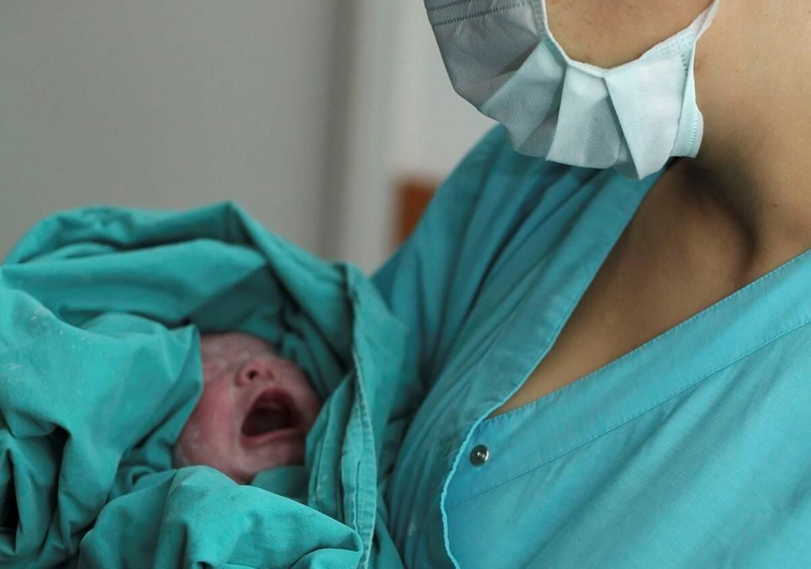 Una matrona sujeta en brazos a un recién nacido.