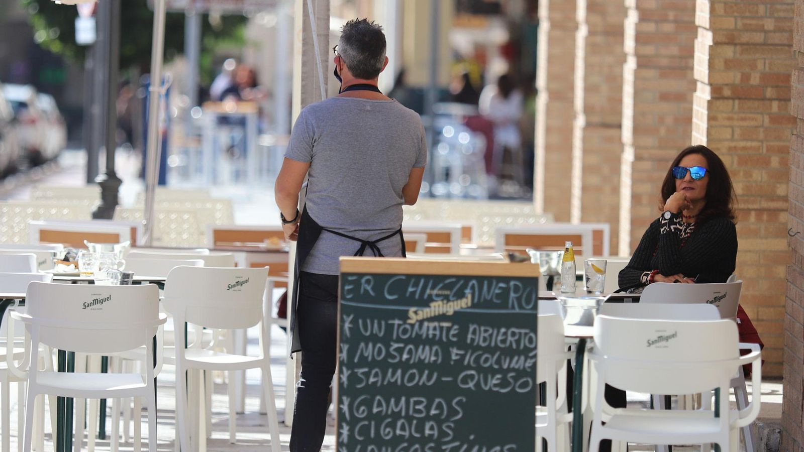 Un camarero aguarda la llegada de clientela a su terraza. Un camarero aguarda la llegada de clientela a su terraza.