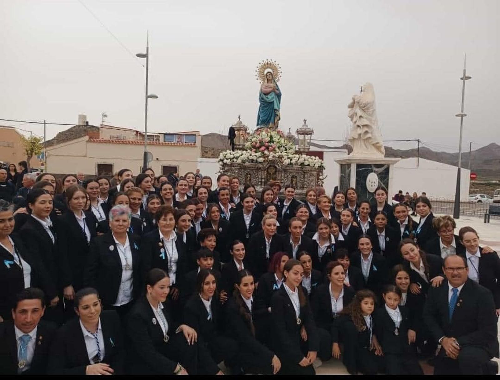 La Virgen del Río junto a la escultura en su honor.