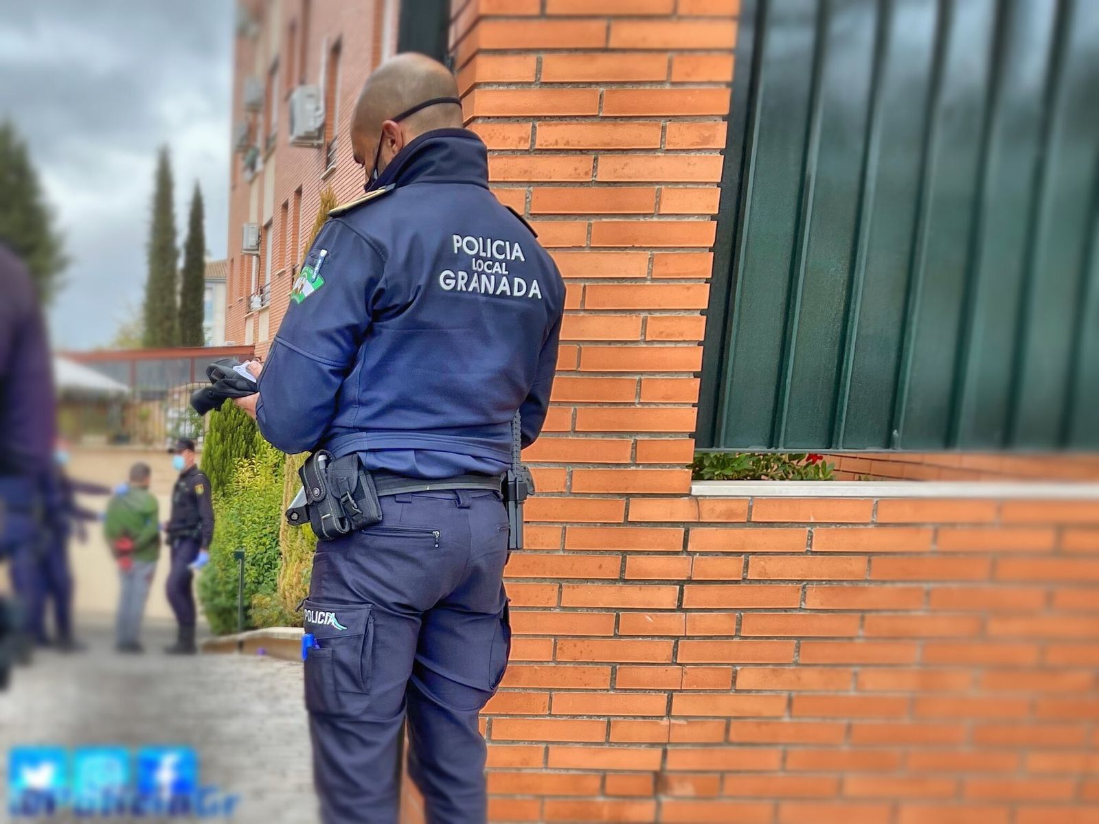 Un policía custodia al presunto asesino, con chaquetón verde