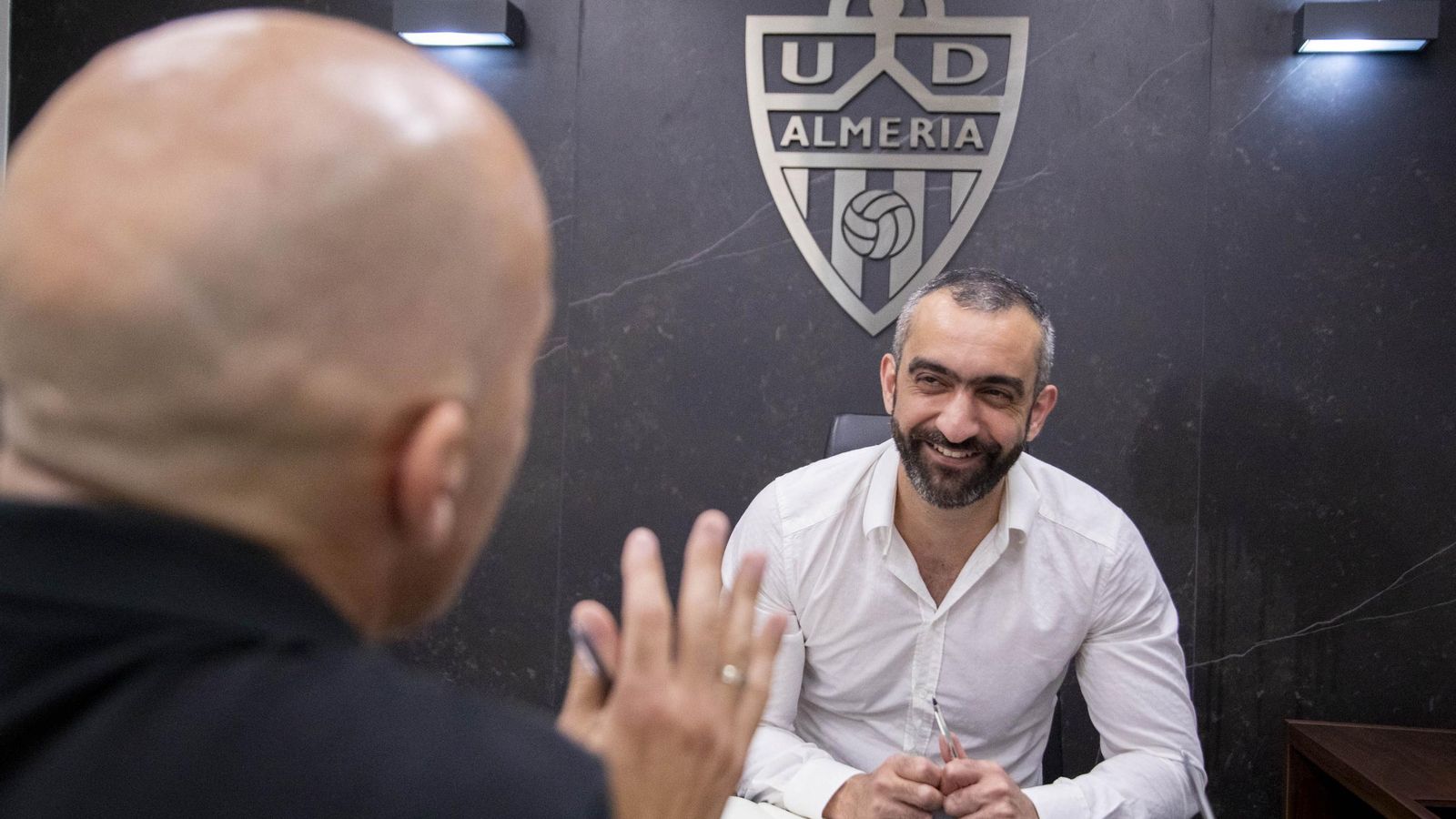 El Assy sonríe en su despacho, presidido por un gran escudo de la UDA, durante un momento de la entrevista