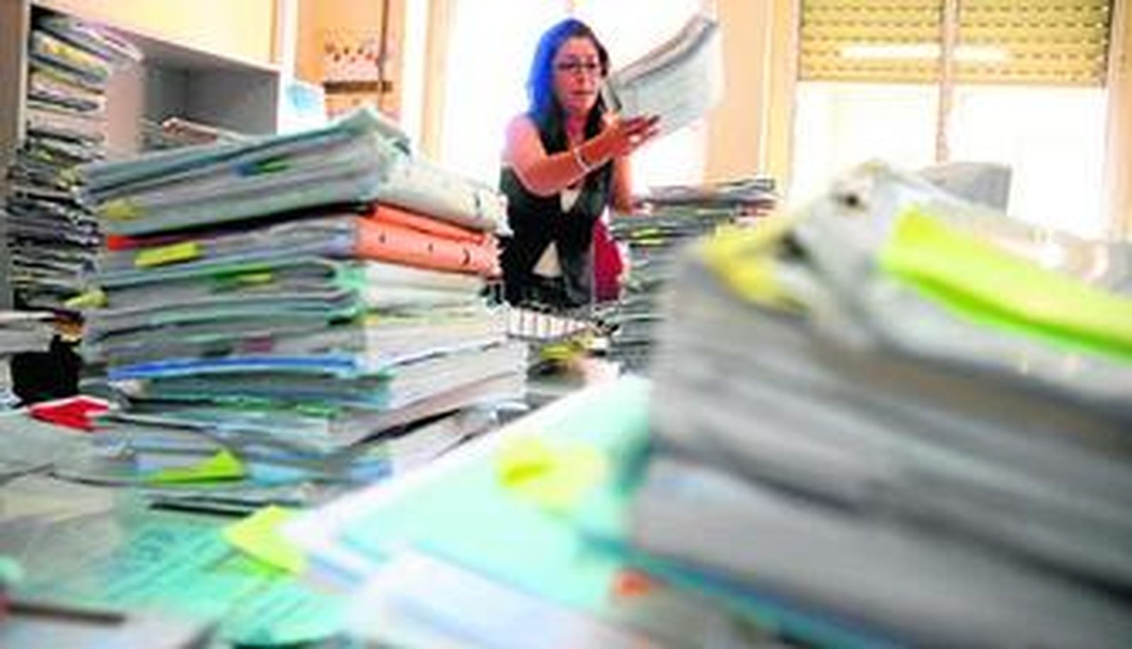 Una funcionaria trabaja en un juzgado de Sevilla, en medio de varias montañas de expedientes.
