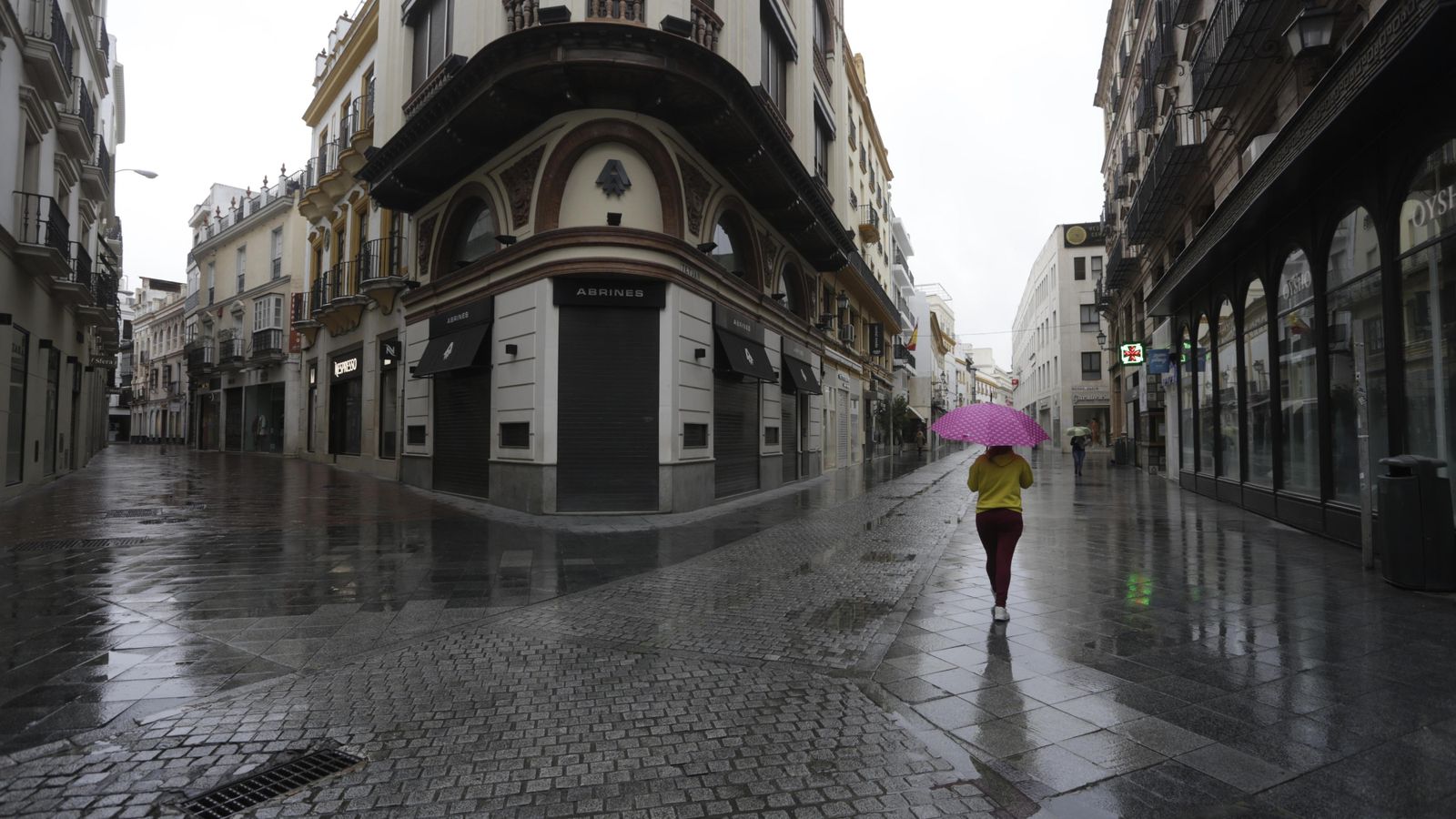 Una joven camina bajo la lluvia por la calle Tetuán.