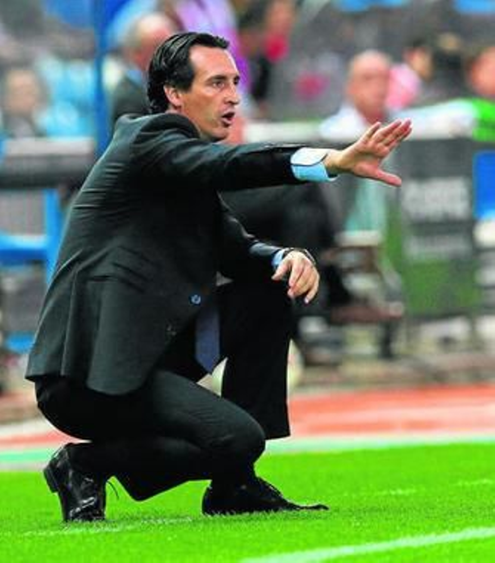 Unai Emery, de cuclillas, dirige a su equipo en un partudo.