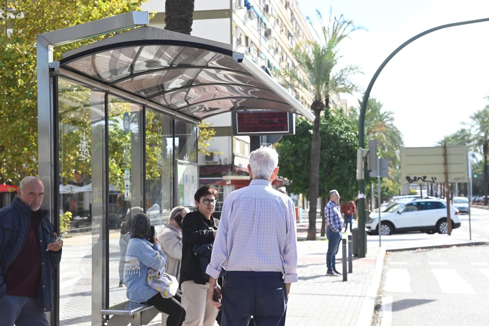 Varias personas esperan la llegada de un autobús de Aucorsa en una parada