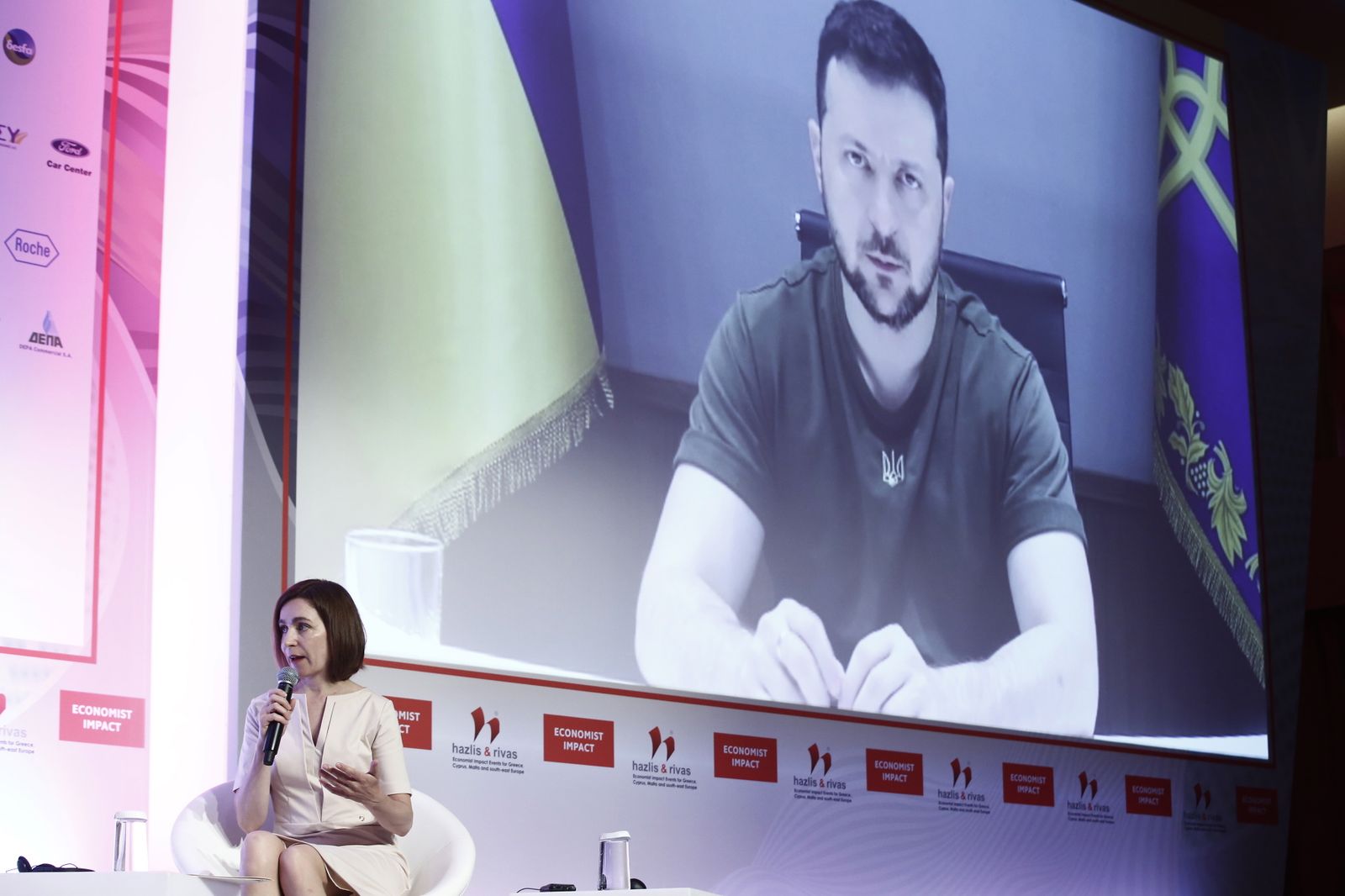 La presidenta moldava,  Maia Sandu, habla mientras el presidente ucraniano, Volodimir Zelenski, aparece en pantalla.