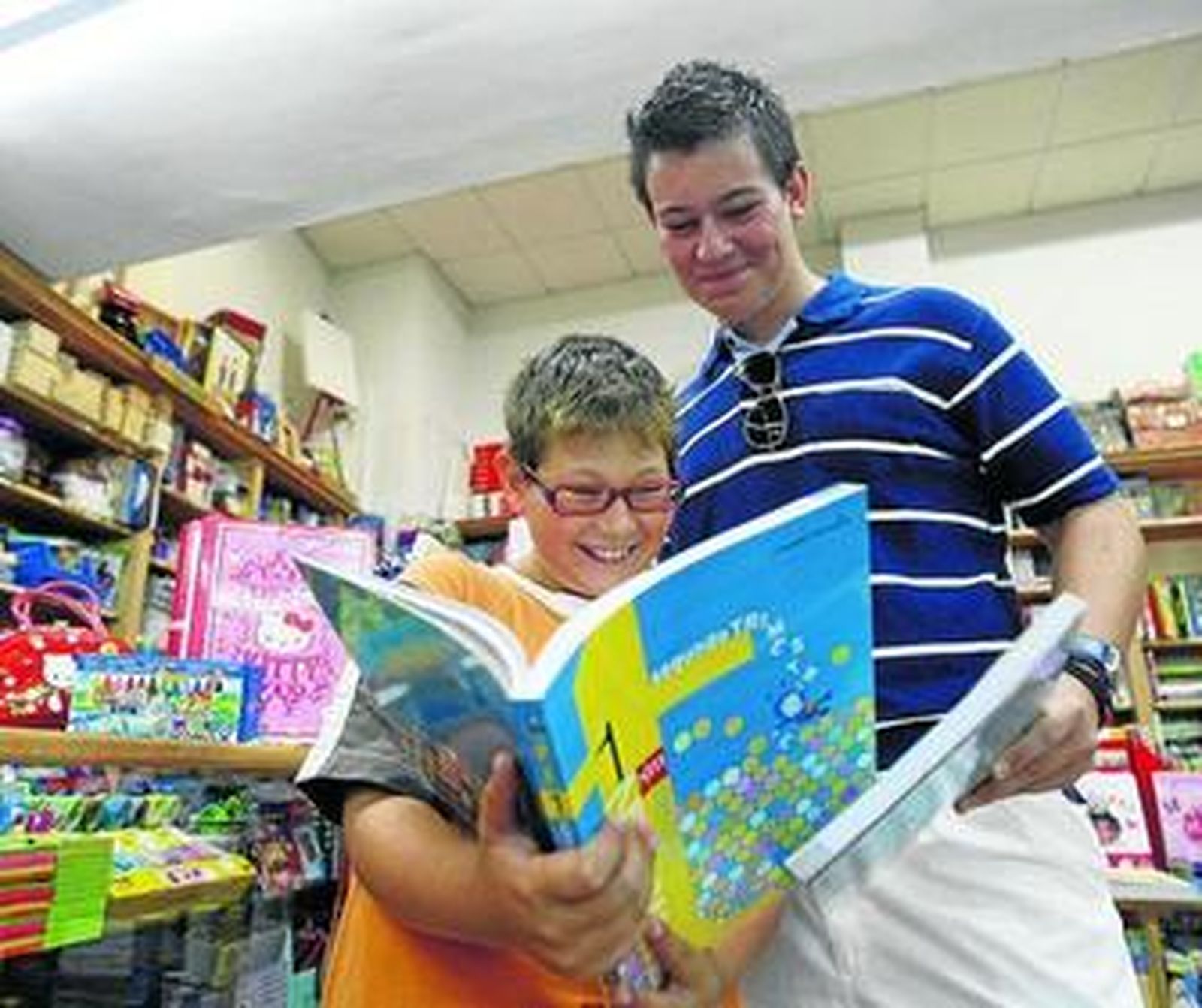 Unos niños miran un libro de Primaria en una librería de la ciudad.