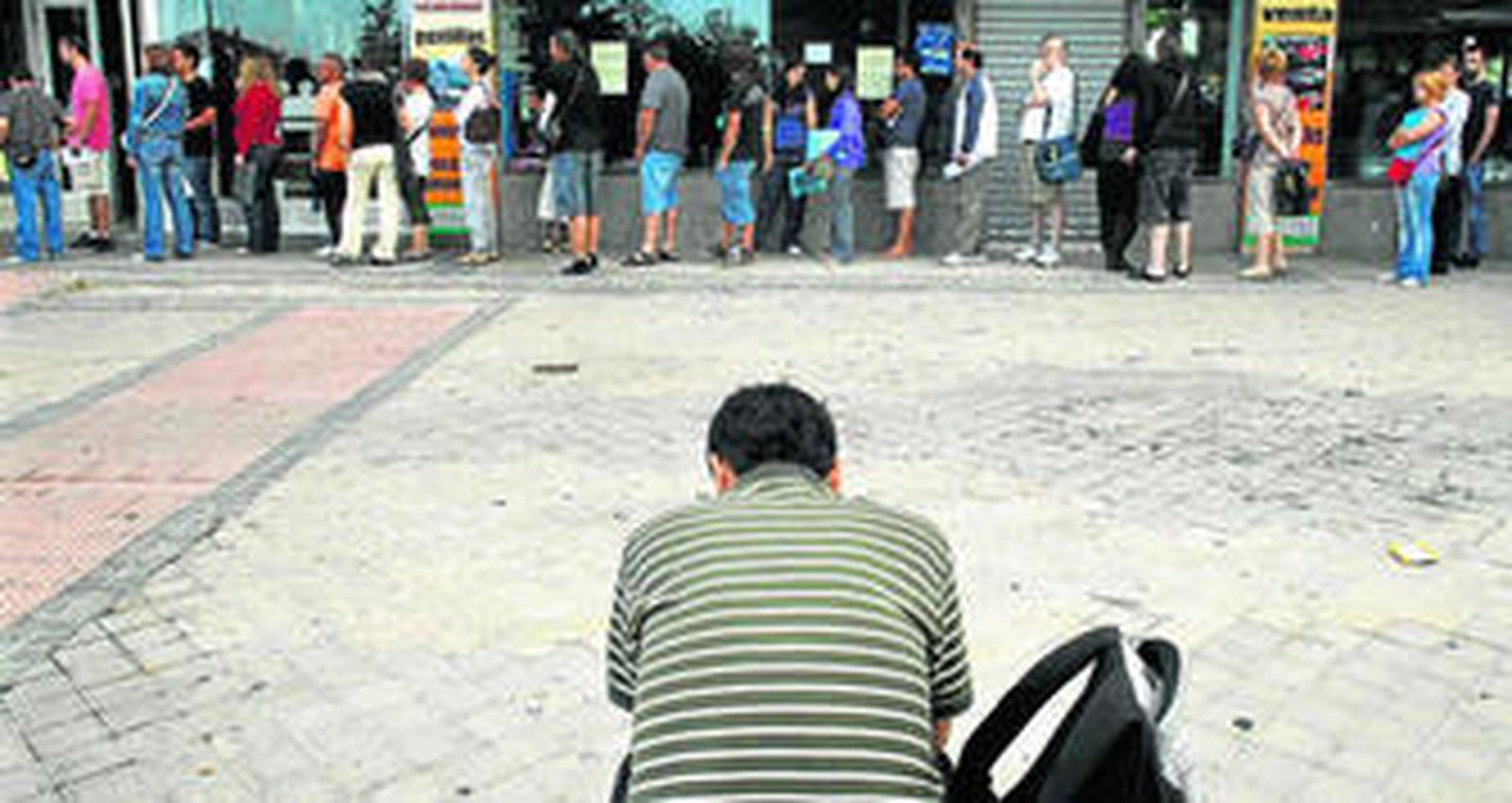 Cola de desempleados ante la puerta de una oficina de empleo en Madrid.