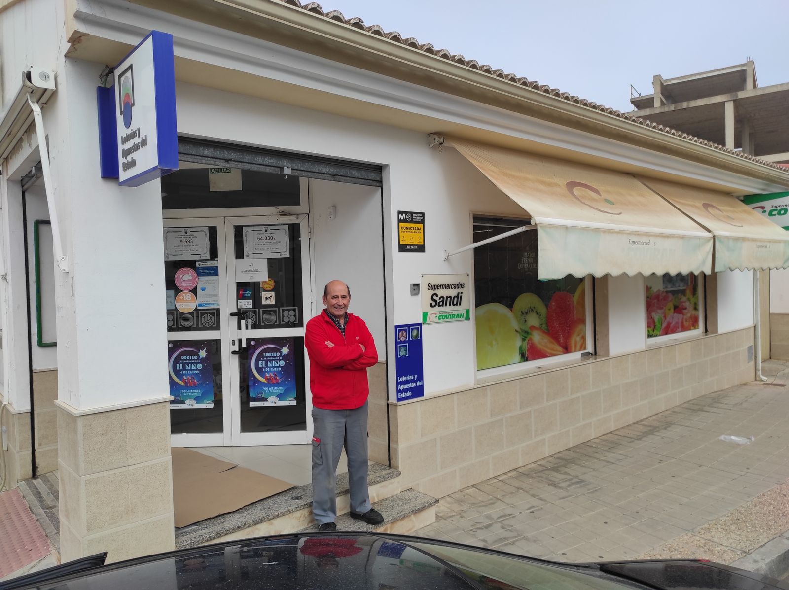 Antonio Dionisio Peña posa en la puerta de su supermercado, que ha entregado el segundo premio del Sorteo del Niño