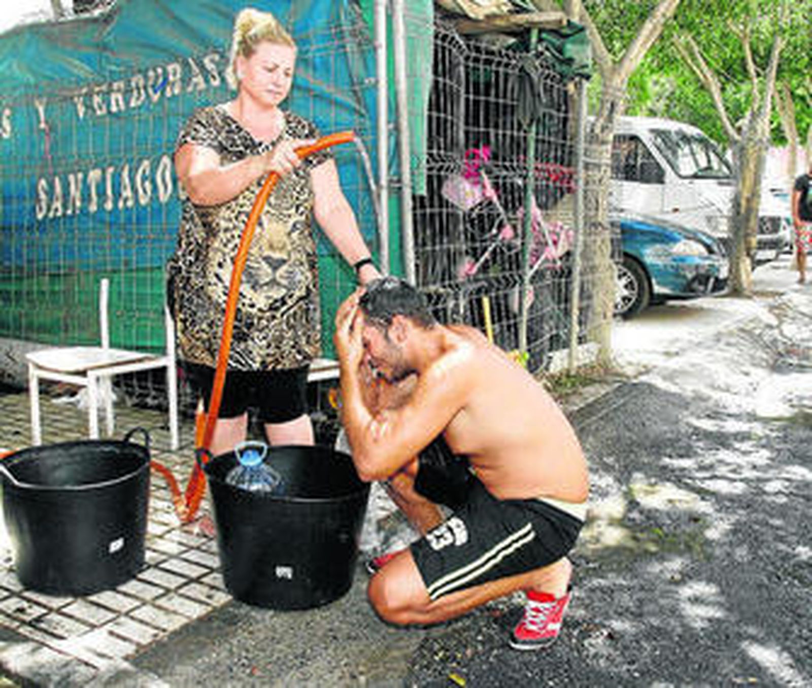 Algunos vecinos utilizan una boca de riego, el único punto de agua del barrio, para ducharse.