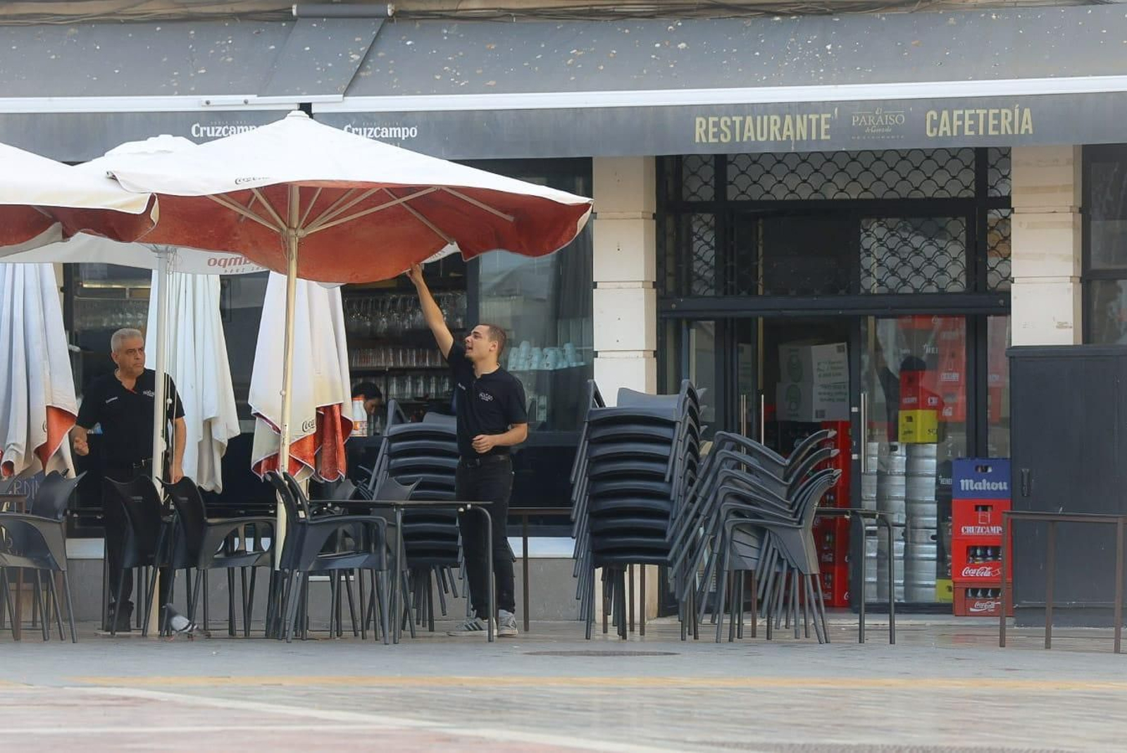 Un camarero saca la sombrilla en la terraza de un establecimiento de Huelva.