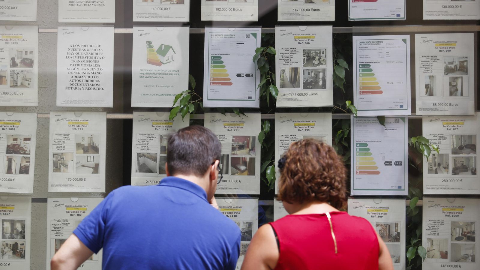 Dos personas observan el escaparate de una inmobiliaria.