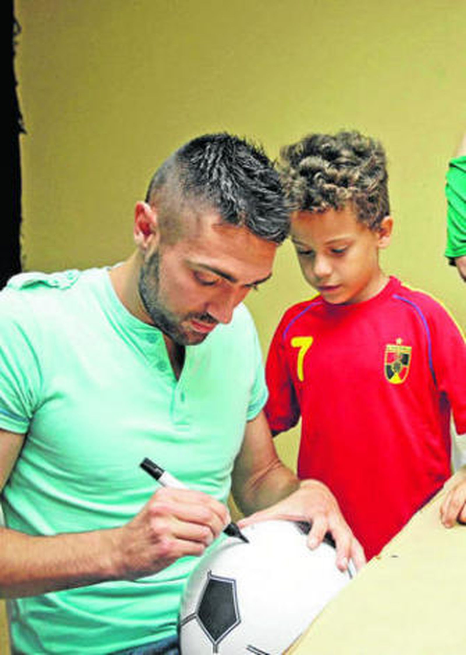 Olmo firma un balón durante un acto en el colegio Velada.