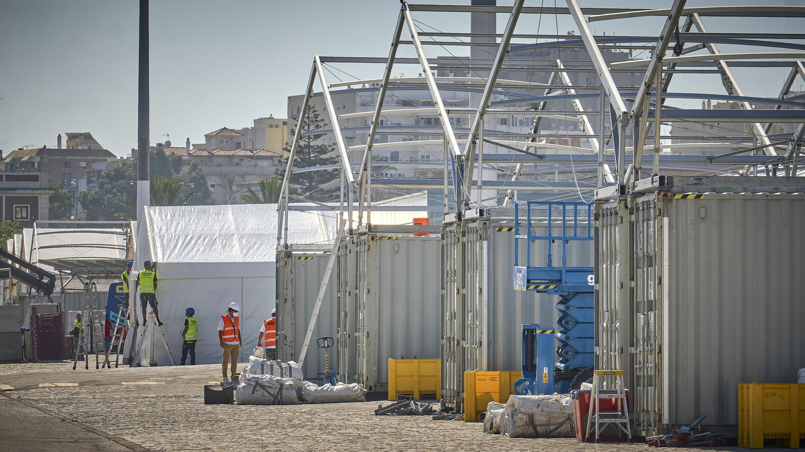 Obreros trabajan en el montaje de las carpas (hangares) en la explanada del muelle comercial .iz