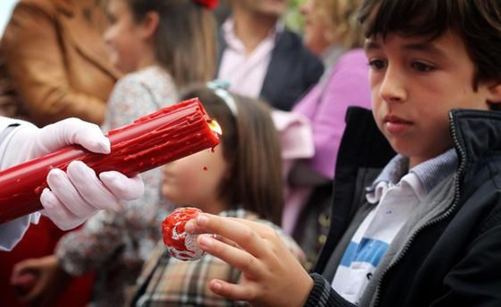 Atractivo infantil. Típica estampa de un niño pidiendo cera roja a uno de los penitentes de La Cena tras su salida.

Foto: Miguel Ángel González