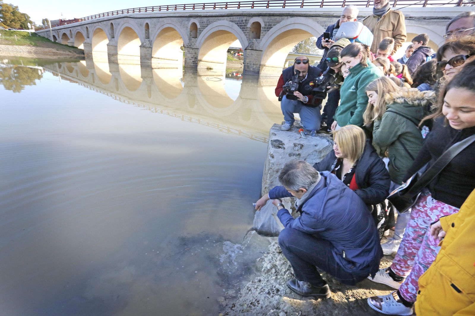 Momento en el que el delegado de Medio Ambiente, Angel Acuña, y la alcaldesa depositan en el Guadalete una bolsa repleta de angulas.