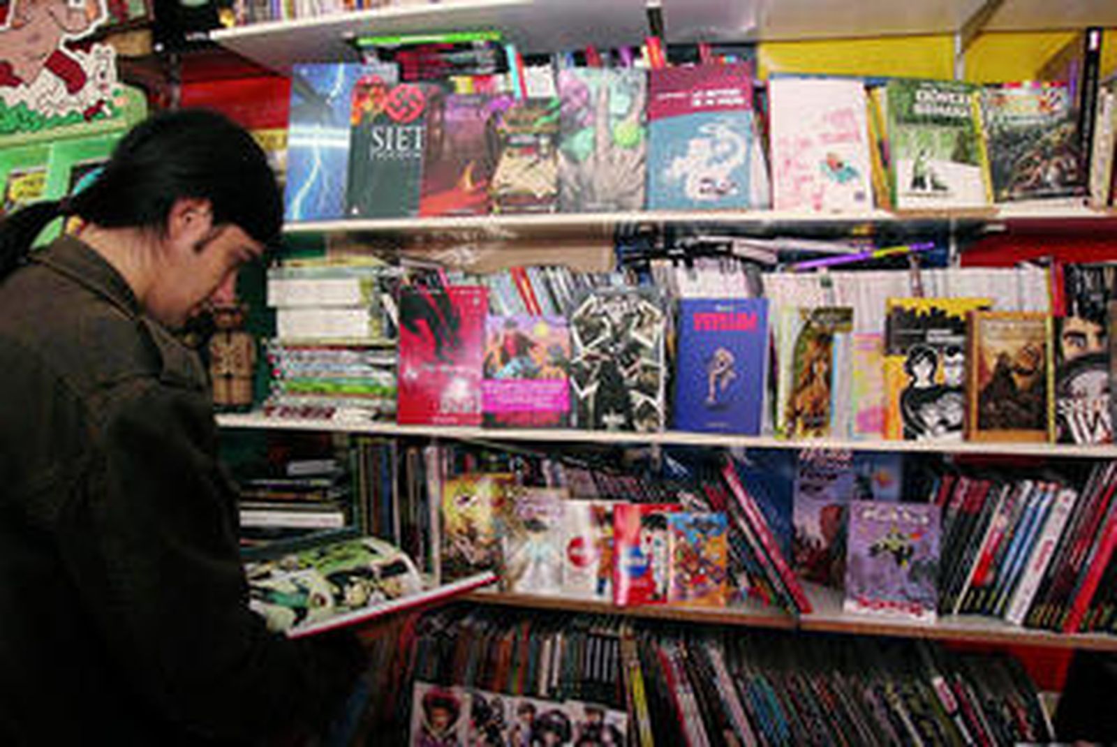 Un joven ojea cómics en una tienda especializada.