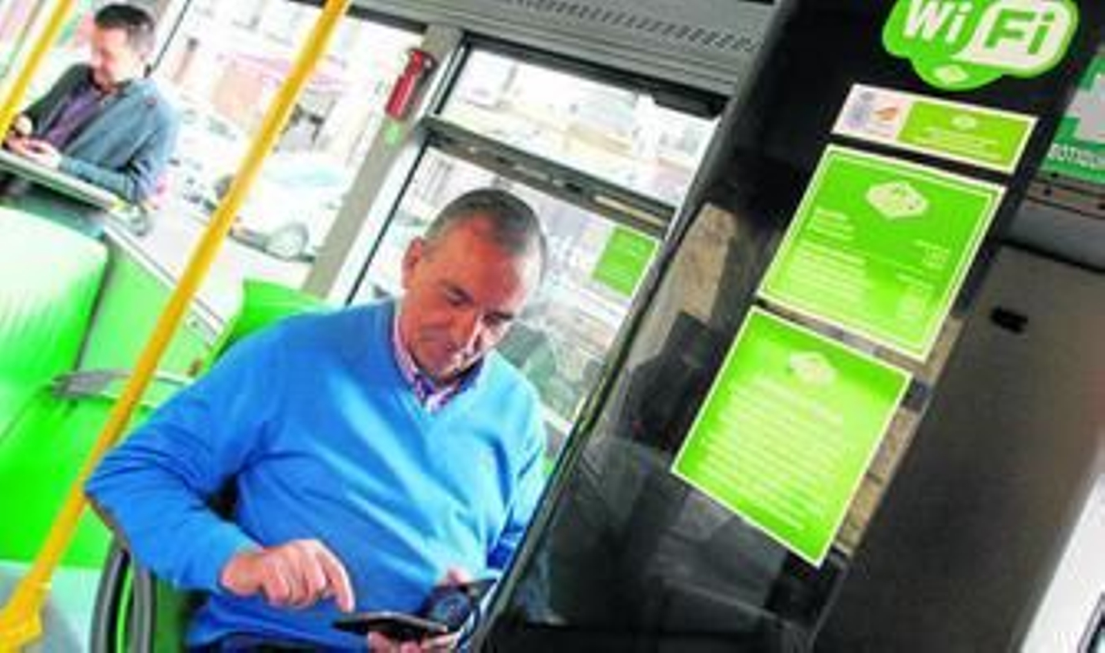 Unos usuarios comprueban la red wifi que se ha instalado en un autobús de Aucorsa.