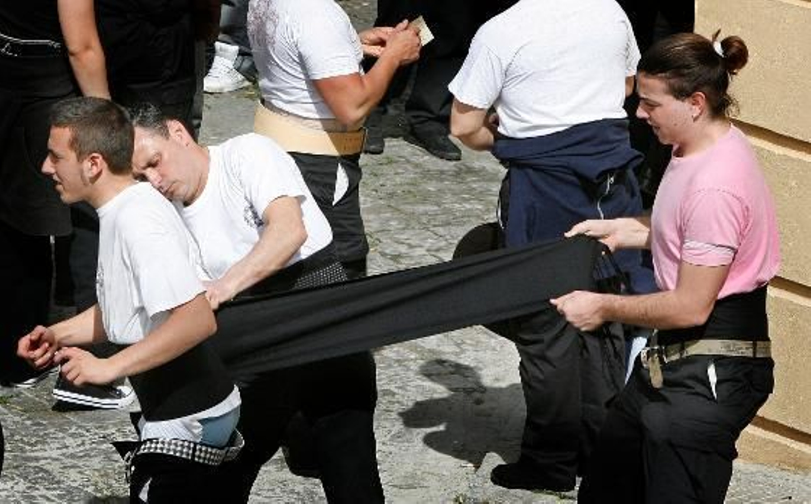 Costaleros ayudan a fajarse a otro, minutos antes de ponerse bajo las trabajaderas.

Foto: Pascual