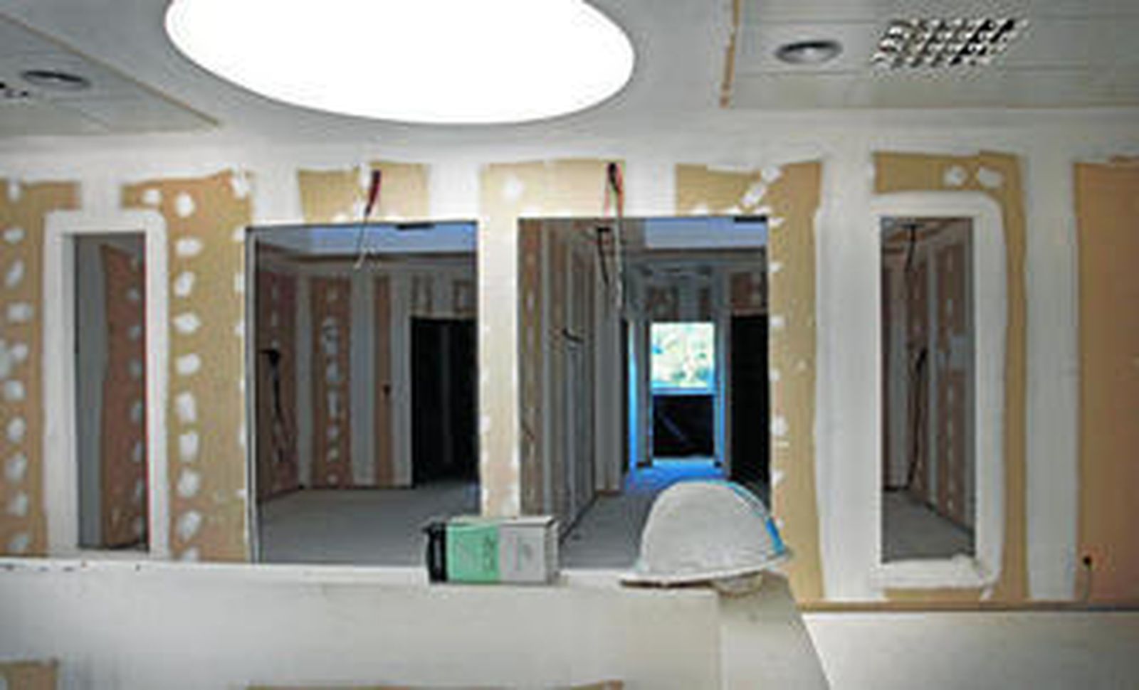 Un casco de obra que hace mucho que no se utiliza ante la zona de hospitalización, con las habitaciones acabadas, pero sin pintar y sin camas.