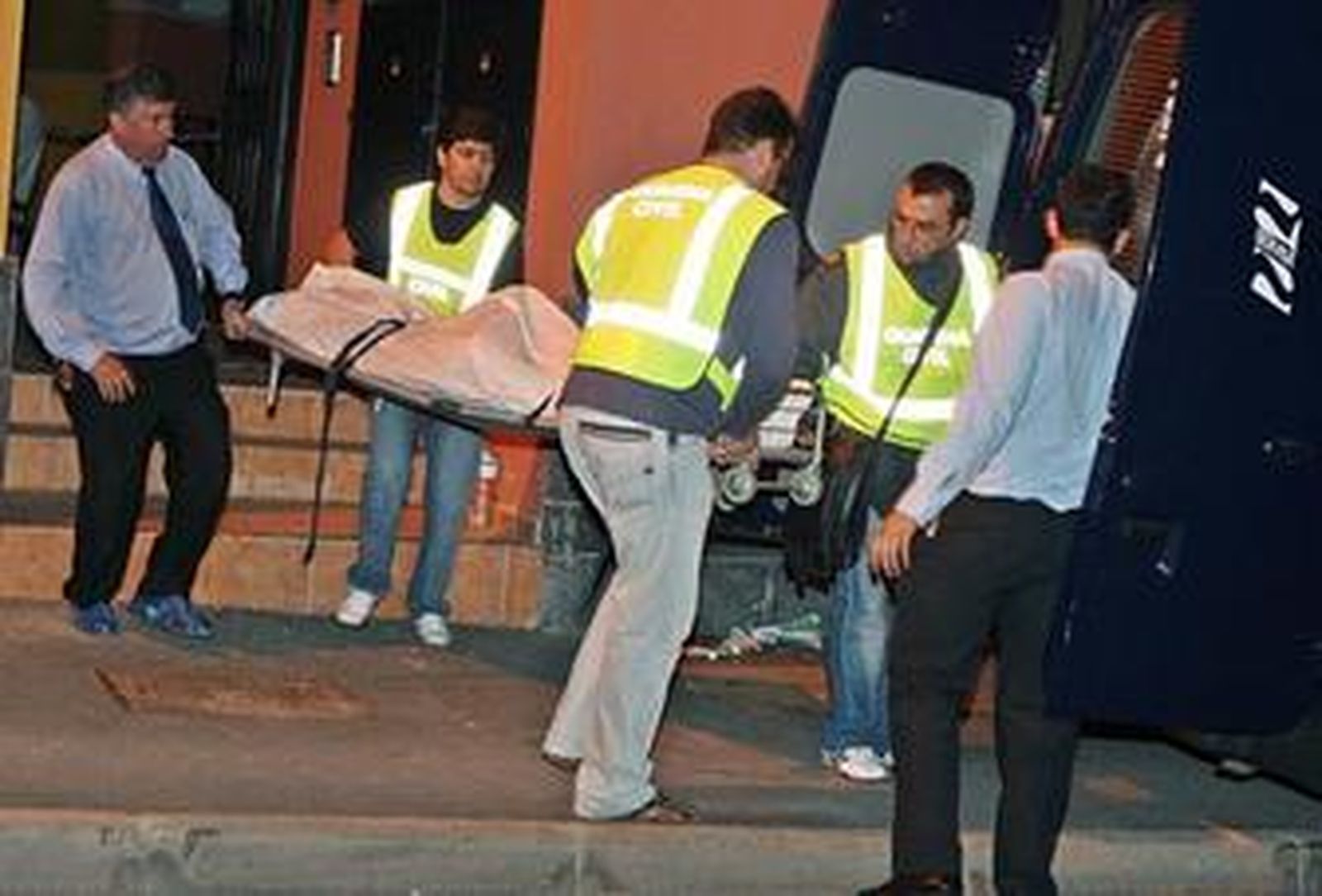 Miembros de los servicios funerarios trasladan el cadáver de una de las cuatro víctimas.