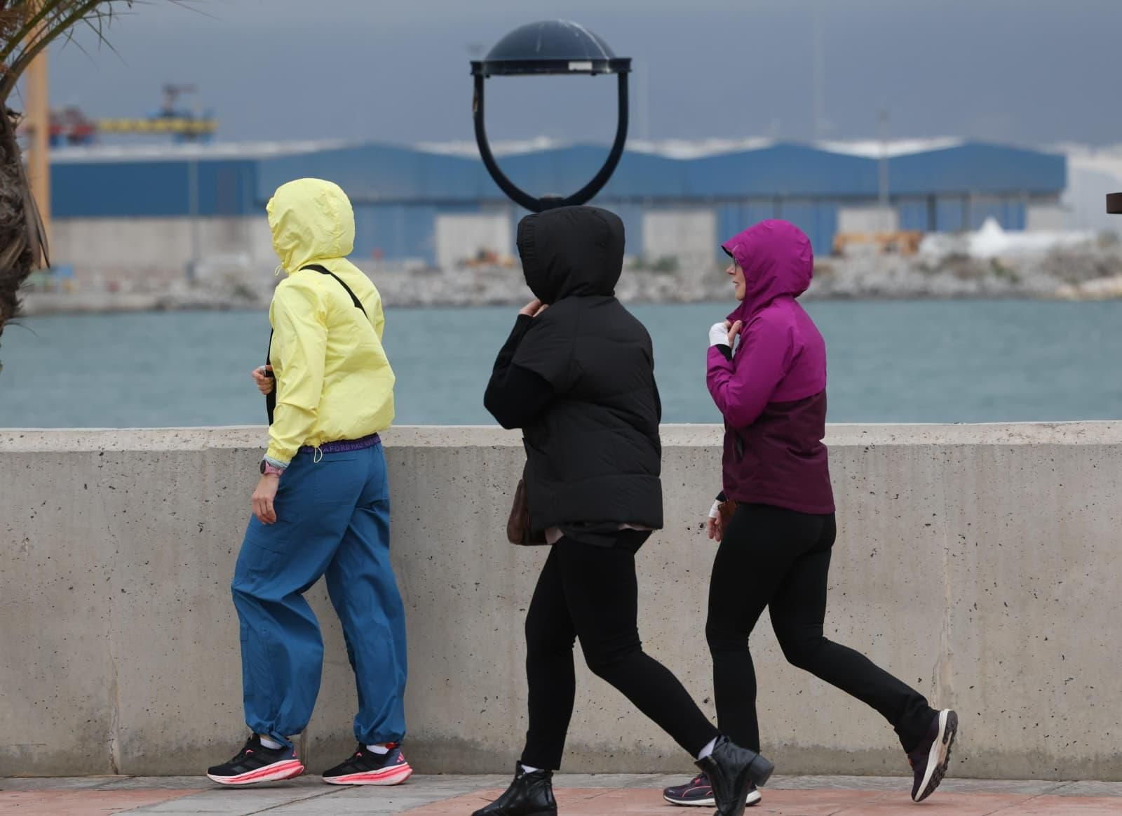 Un grupo se protege con gorros de la lluvia y el viento en Málaga.