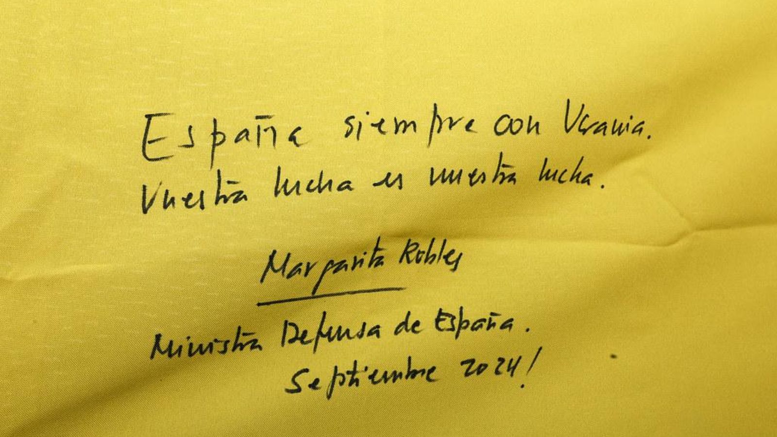 Dedicatoria que la ministra Margarita Robles escribió en la bandera de Ucrania para sus soldados.
