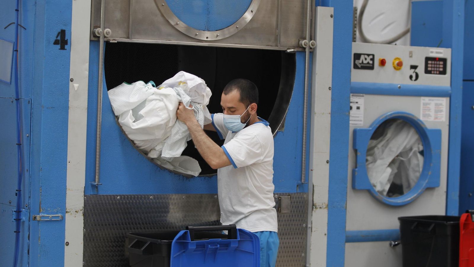 Uno de los trabajadores saca sábanas de una de las máquinas donde ha sido tratada