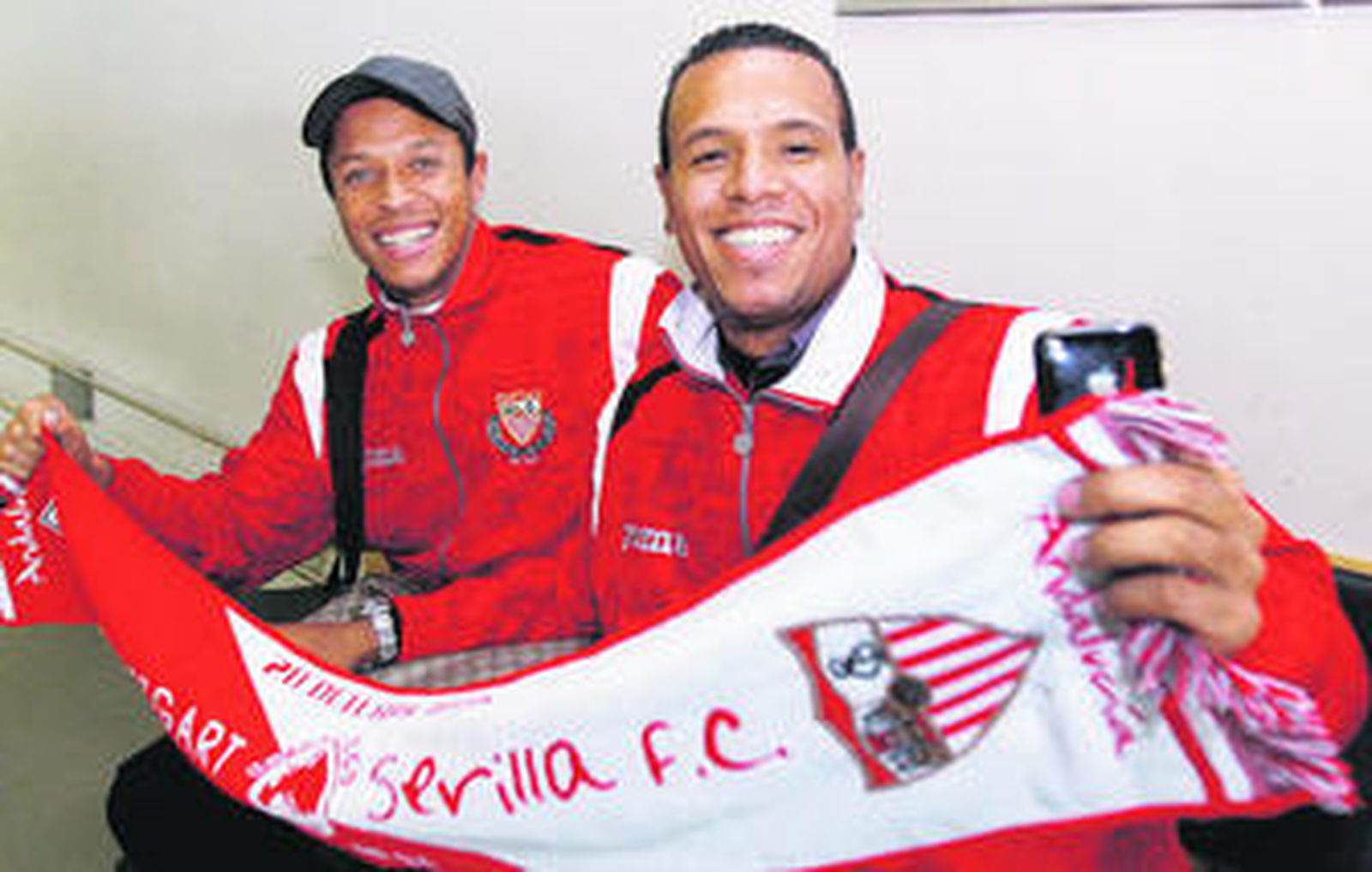 Adriano y Luis Fabiano, muy sonrientes, posan con la bufanda conmemorativa del partido en el aeropuerto de Stuttgart.
