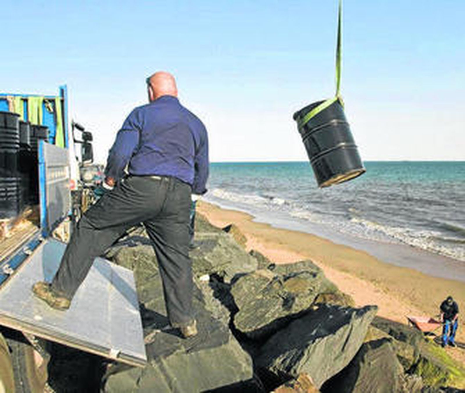 Un operario de Cepsa participa en la retirada de vertidos en una playa de Huelva.