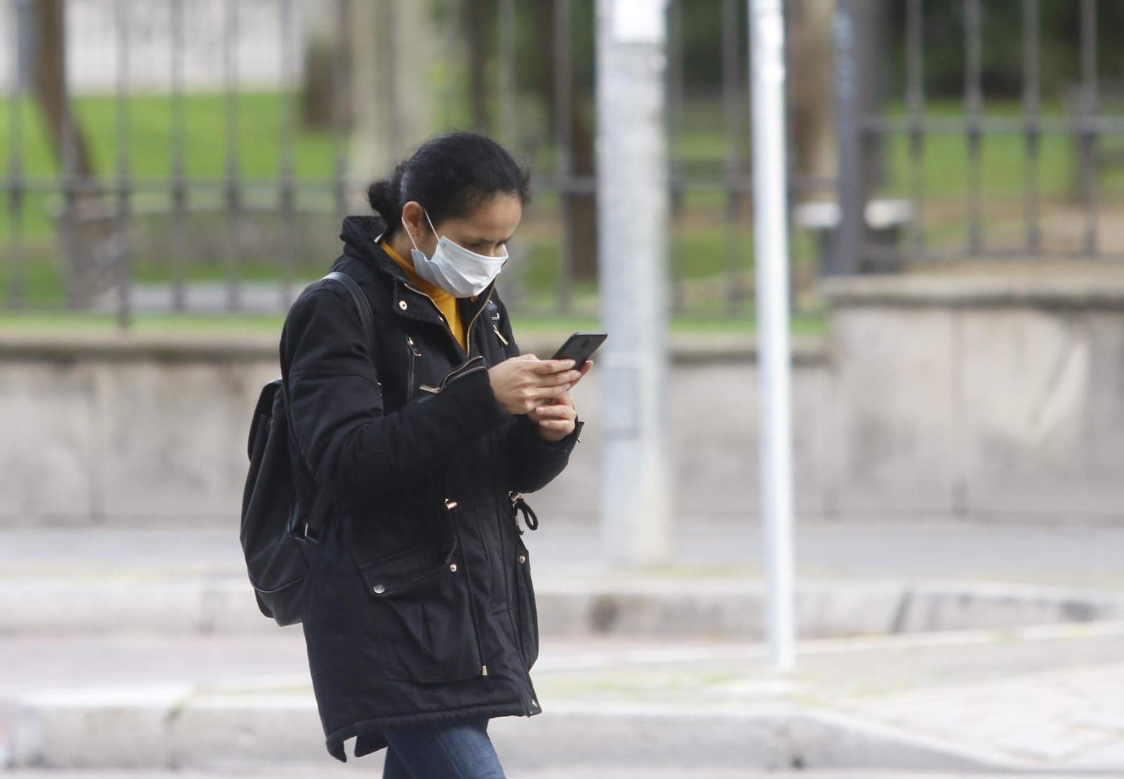 Una joven camina por la calle protegida por una mascarilla.